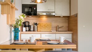Een moderne keuken met een magnetron, koffiezetapparaat en een houten snijplank.