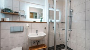 Een badkamer met een wastafel, spiegel, douche en toilet.
