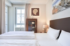 Ein Hotelzimmer mit einem großen Bett, einem Holzschrank, einem Gemälde an der Wand und einem Fenster mit Vorhängen.