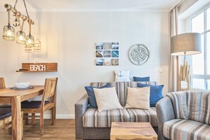 Ein gemütliches Wohnzimmer mit einer Couch, einem Esstisch und einer Deckenleuchte.