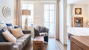 Ein Hotelzimmer mit einer Couch, einem Sessel, einem Holztisch und einem Bett.
