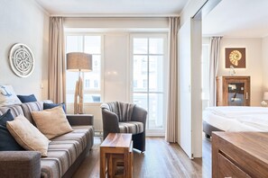 Ein Hotelzimmer mit einer Couch, einem Sessel, einem Holztisch und einem Bett.