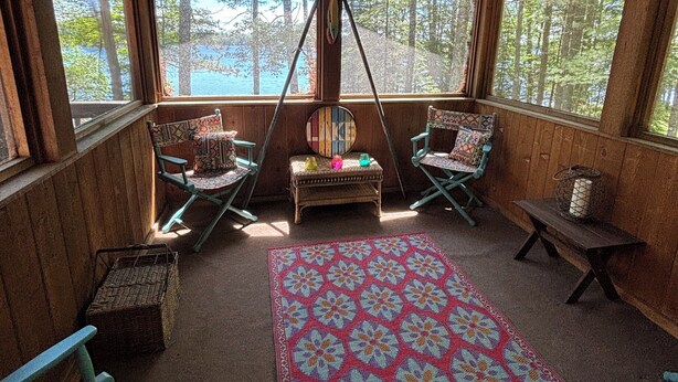 A cabin with a large window, a wooden ceiling, and a colorful rug. - Beautiful 3 bed/2bath updated cabin w sandy swimmable frontage & great fishing (Eagle River)