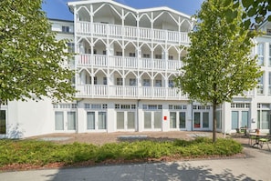 Ein weißes Gebäude mit einer symmetrischen Fassade, mehreren Balkonen und einem gepflasterten Innenhof.