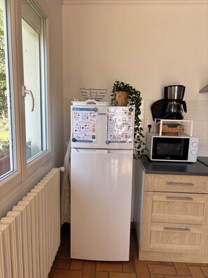 Eine Küche mit einem weißen Kühlschrank, einer Mikrowelle und einer Kaffeemaschine auf der Arbeitsfläche.