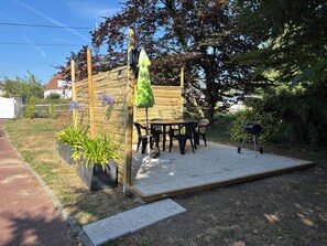 Un espace patio agrémenté d’une clôture en bois, de meubles d’extérieur, d’un barbecue et de plantes en pot.