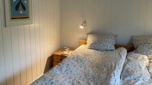 A bedroom with a bed, a nightstand, a wall-mounted lamp, and a framed picture. - Modern wooden house near Kollerup Forest (Fjettitslev)