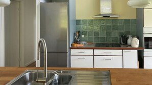 A kitchen with a stainless steel sink, a refrigerator, and a countertop with various kitchen items. - Modern wooden house near Kollerup Forest (Fjettitslev)