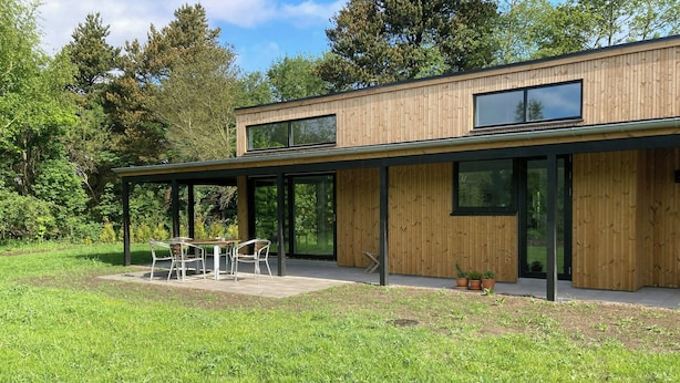 A modern house with a wooden exterior, large windows, and a patio with outdoor furniture. - Modern wooden house near Kollerup Forest (Fjettitslev)