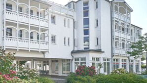 Ein mehrstöckiges Hotel mit Balkonen, großen Fenstern und einem Garten mit Blumen.