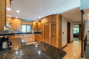 A modern kitchen with wooden cabinets, granite countertops, and stainless steel appliances.