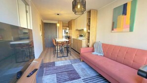A modern living room with a sofa, TV, and dining area. - Rbk Dpto GIM-3 personas-Lavanderia-WIFI (Santiago)