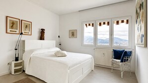 Ein Schlafzimmer mit einem Bett, einem Sessel, einer Heizung und einem Fenster mit Blick.