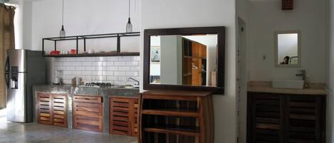 Una cocina moderna con una isla central, armarios de madera y un espejo grande sobre el lavamanos.