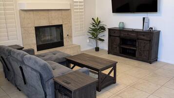 Una sala de estar con un sofá modular, una mesa de centro, una chimenea, un televisor y un mueble bajo para la televisión.
