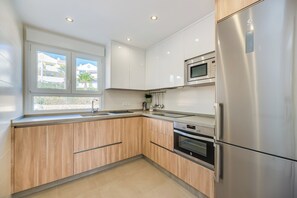Eine moderne Küche mit Holzausstattung, Edelstahlgeräten und einem Fenster mit Blick auf Gebäude.