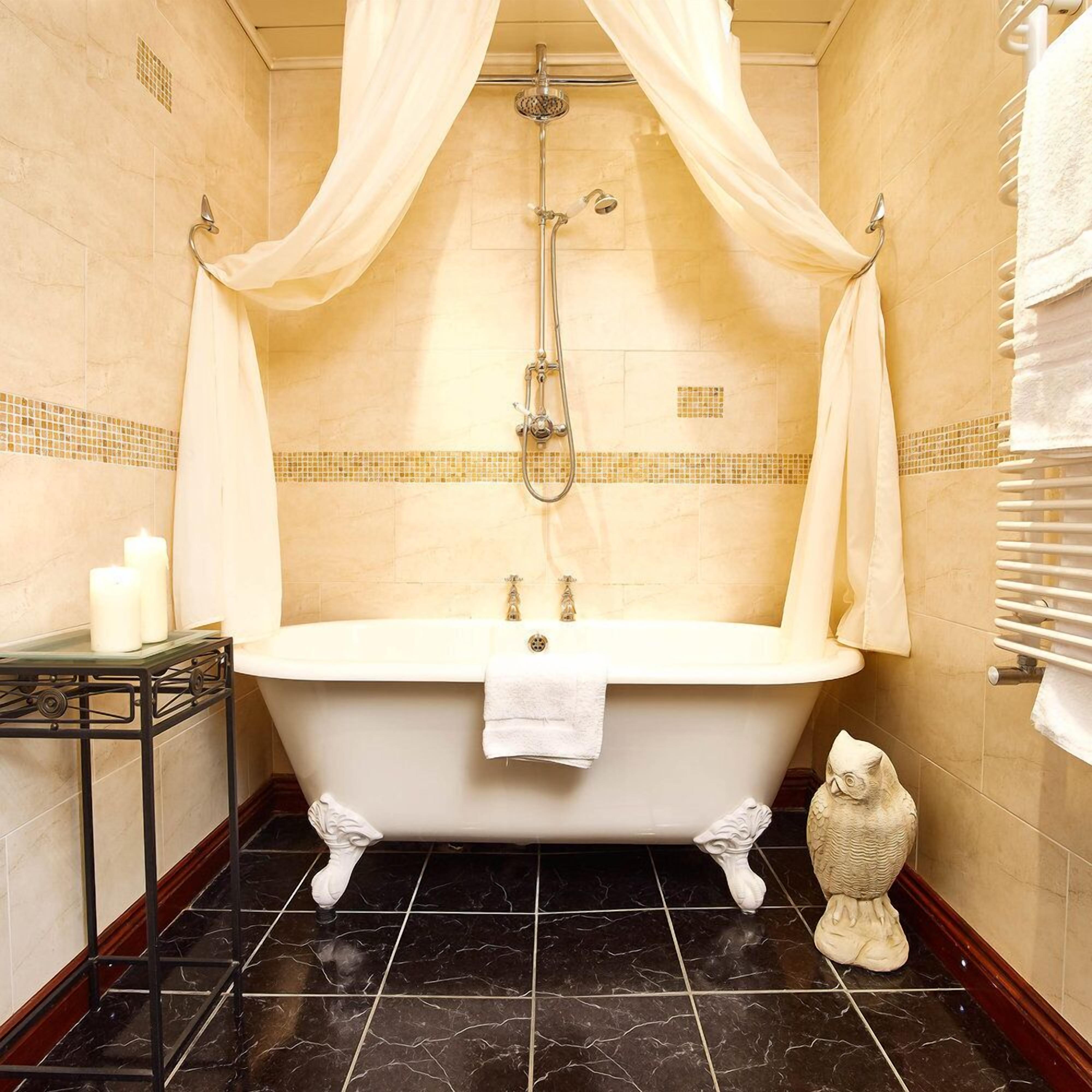 Une salle de bain avec une baignoire sur pieds, une pomme de douche et une statue décorative représentant un hibou.