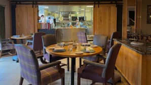 Een eethoek met een ronde tafel, stoelen en uitzicht op de keuken.
