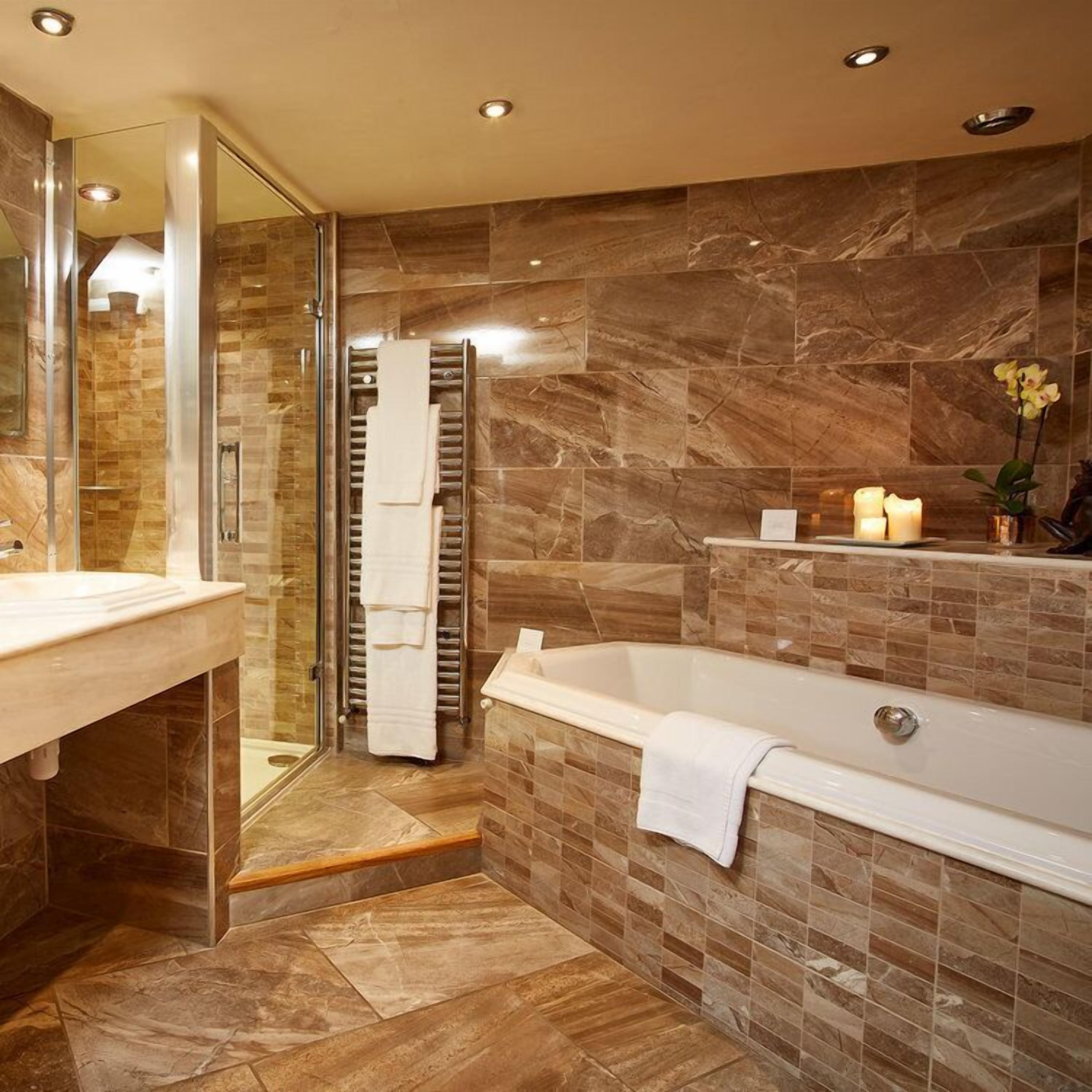 Een moderne badkamer met een glazen douchecabine, een vrijstaand bad en een betegelde wand van marmer.