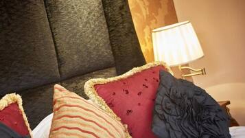 A bed with a tufted headboard, multiple pillows, and a bedside lamp.