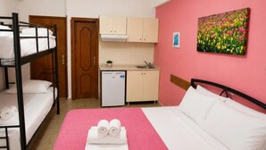 A room with bunk beds, a single bed, a kitchenette, and a painting of flowers. - Gallery (Ammouliani)