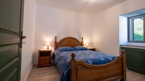 Ein Schlafzimmer mit einem Holzbett, zwei Nachttischen mit Lampen, einem Fenster mit Blick und einer grünen Tür.