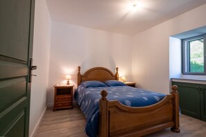 Ein Schlafzimmer mit einem Holzbett, zwei Nachttischen mit Lampen, einem Fenster mit Blick und einer grünen Tür.