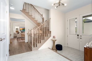 A staircase with wooden balusters, a white door, and a small round table with a vase.