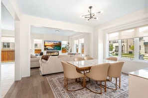 A spacious living room with a large dining table, comfortable seating, and a fireplace.