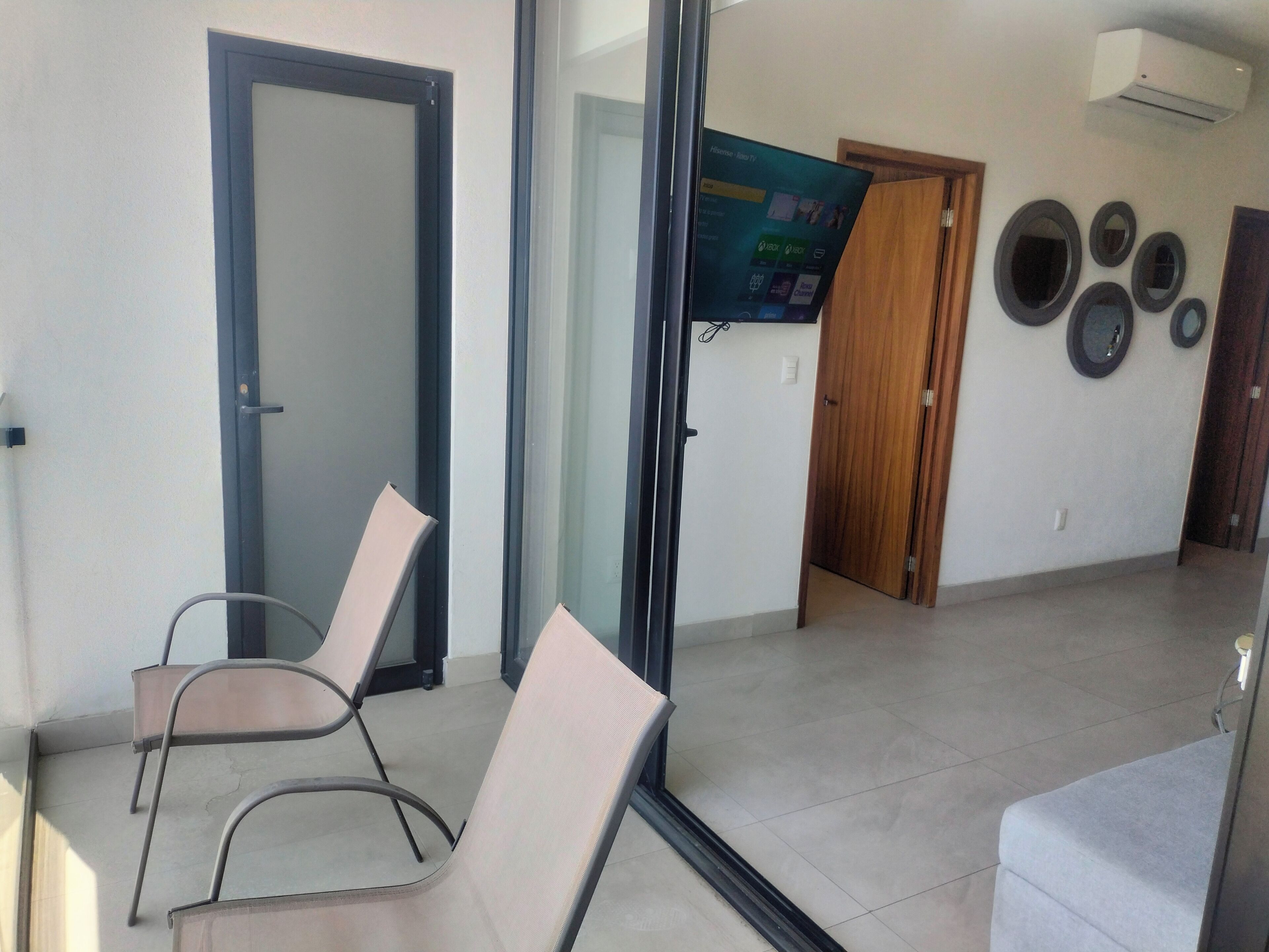 A room with a glass door, a television, and a wall with circular mirrors.