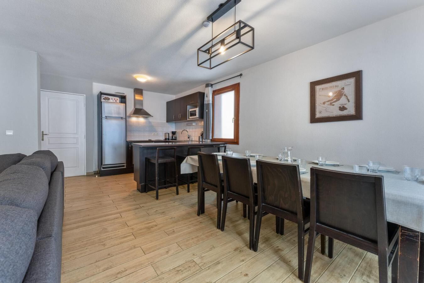 Une cuisine moderne dotée d’un îlot central, d’une table à manger et de chaises. On y trouve également un réfrigérateur, un four à micro-ondes et un évier.