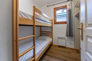 A bunk bed room with a window, a radiator, and a door. - 300m from ski slopes, swimming pool, sauna, hammam, terrace, fireplace or stove, parking, tv (Les Orres)