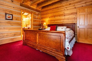 Ein schlicht eingerichtetes Schlafzimmer im Chalet-Stil mit einem großen Bett, einer Holzkommode und einem roten Teppich.