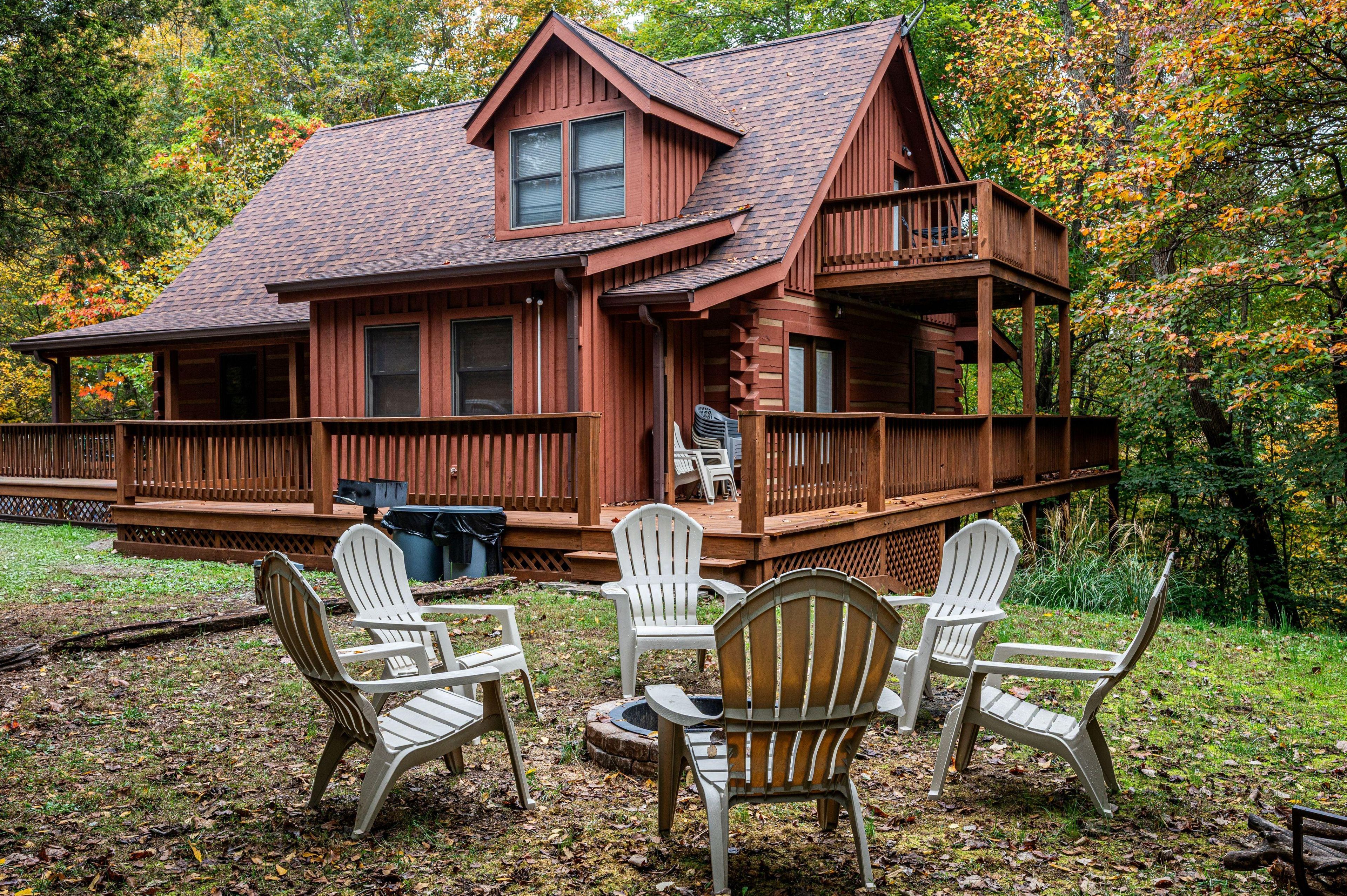 A cabin with a deck, multiple windows, and outdoor seating.