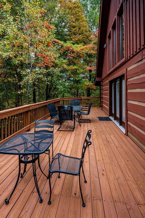 Eine Holzterrasse mit Gartenmöbeln, umgeben von Bäumen im Herbstlaub.