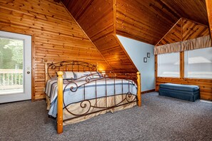 Ein Schlafzimmer mit Holzbalkendecke, einem Bett mit Metallgestell, einer Bank und einem Fenster mit Jalousien.