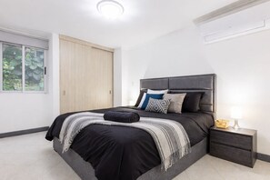 Ein modernes Schlafzimmer mit einem Bett, einem Nachttisch und einem Fenster.