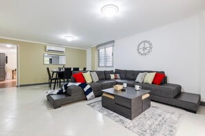 Ein modernes Wohnzimmer mit einer Eckcouch, einem Couchtisch und einem Essbereich mit Stühlen.