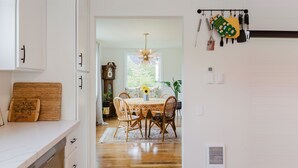 Une cuisine avec des meubles blancs, un plan de travail en bois et un coin repas comprenant une table et des chaises.