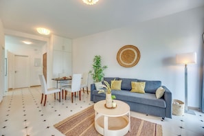 A modern living room with a grey sofa, white chairs, a round coffee table, and a potted plant. - LXR Parador (Reformatted) 1 Bedroom (Benalmádena)