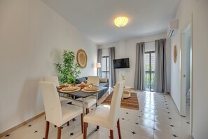 A modern living room with a dining area, a flat-screen TV, and a large window with curtains. - LXR Parador (Reformatted) 1 Bedroom (Benalmádena)
