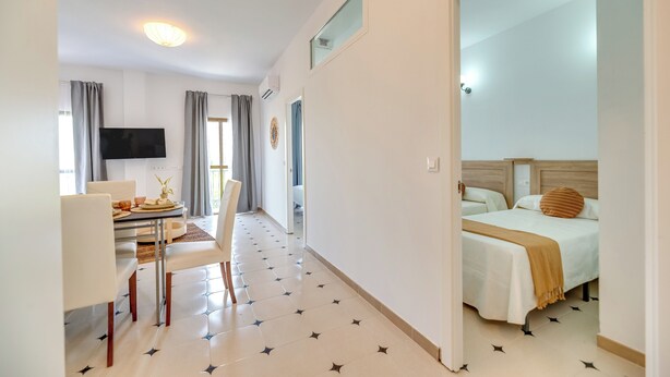 Een hotelkamer met een bed, een bureau met stoelen, een televisie en een eethoek.