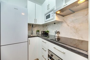 A kitchen with white cabinets, a black countertop, a microwave, and a coffee machine. - LXR Parador (Reformatted) 1 Bedroom (Benalmádena)