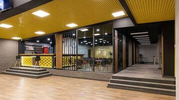 A modern interior with a yellow ceiling, glass partitions, and a staircase leading to an upper level.
