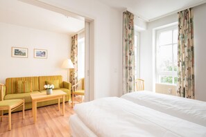 A hotel room with a bed, a sofa, a table, and two chairs. - Lichtdurchflutete Ferienwohnung mit Balkon in Sudostlage in Sellin (Sellin)