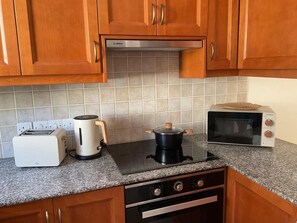 Eine Küche mit Holzausstattung, einer Bosch Dunstabzugshaube, einem Toaster, einer Kaffeemaschine, einer Mikrowelle und einem Herd.