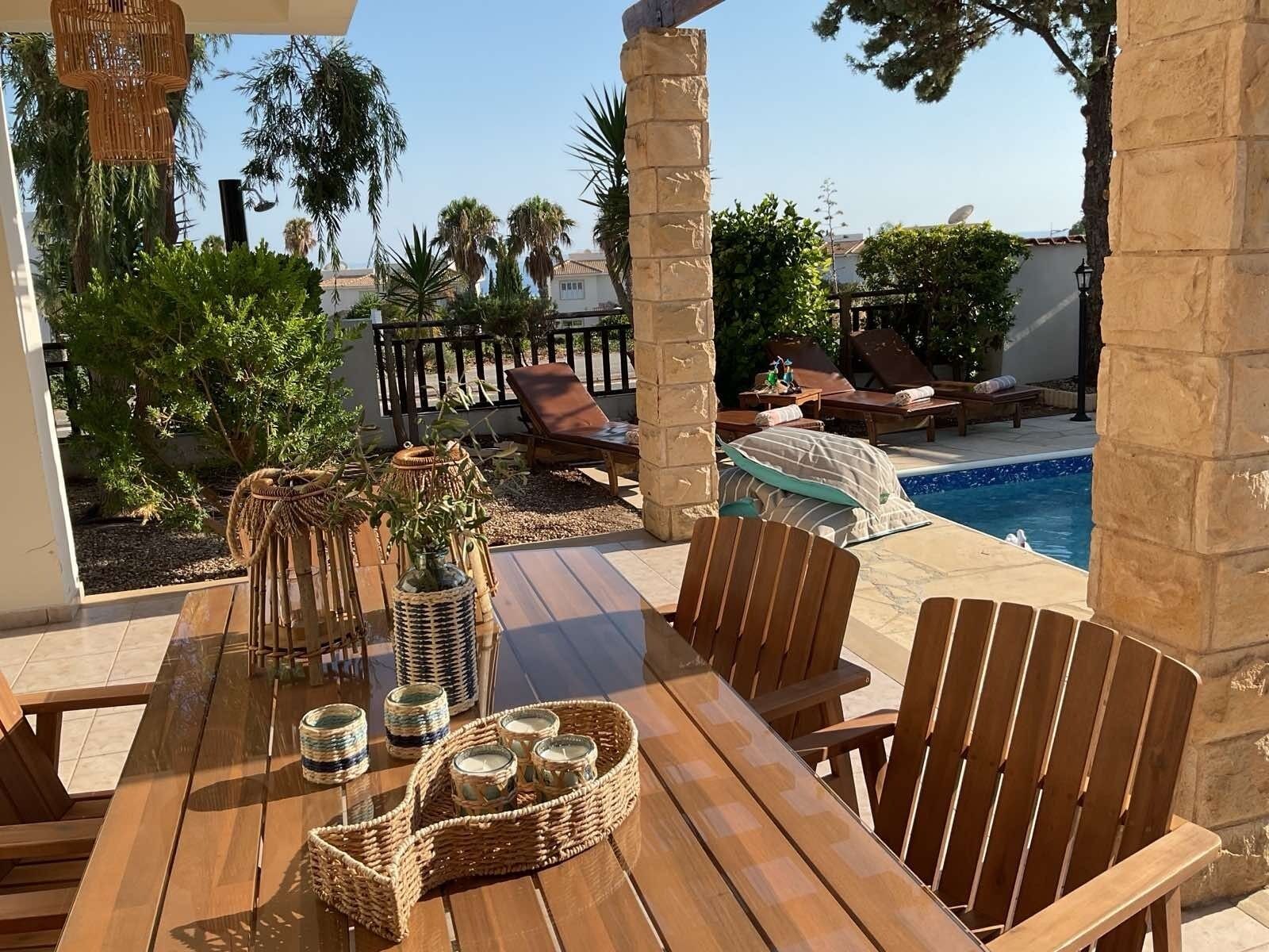 Eine Terrasse im Freien mit Pool, Holzmöbeln und Dekoration.