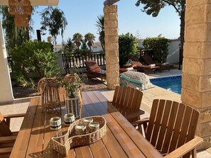 Eine Terrasse im Freien mit Pool, Holzmöbeln und Dekoration.