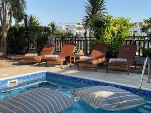 A pool area with lounge chairs and a small pool.