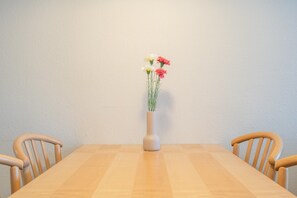 Ein Esstisch mit einer weißen Vase voller Blumen, umgeben von Holzsesseln.